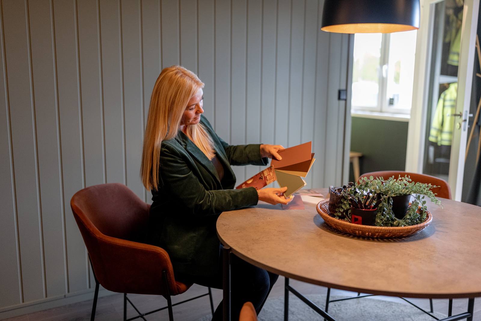 Marita ser på fargeprøver ved et rundt bord i hjemmekoselig miljø