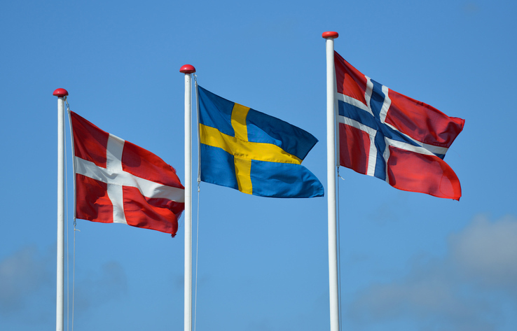 De tre skandinaviske flaggene på rekke mot blå himmel