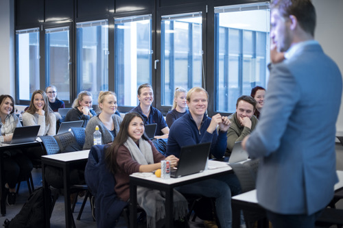 Foto av studenter i klasserom som følger med på en mannlig foreleser.