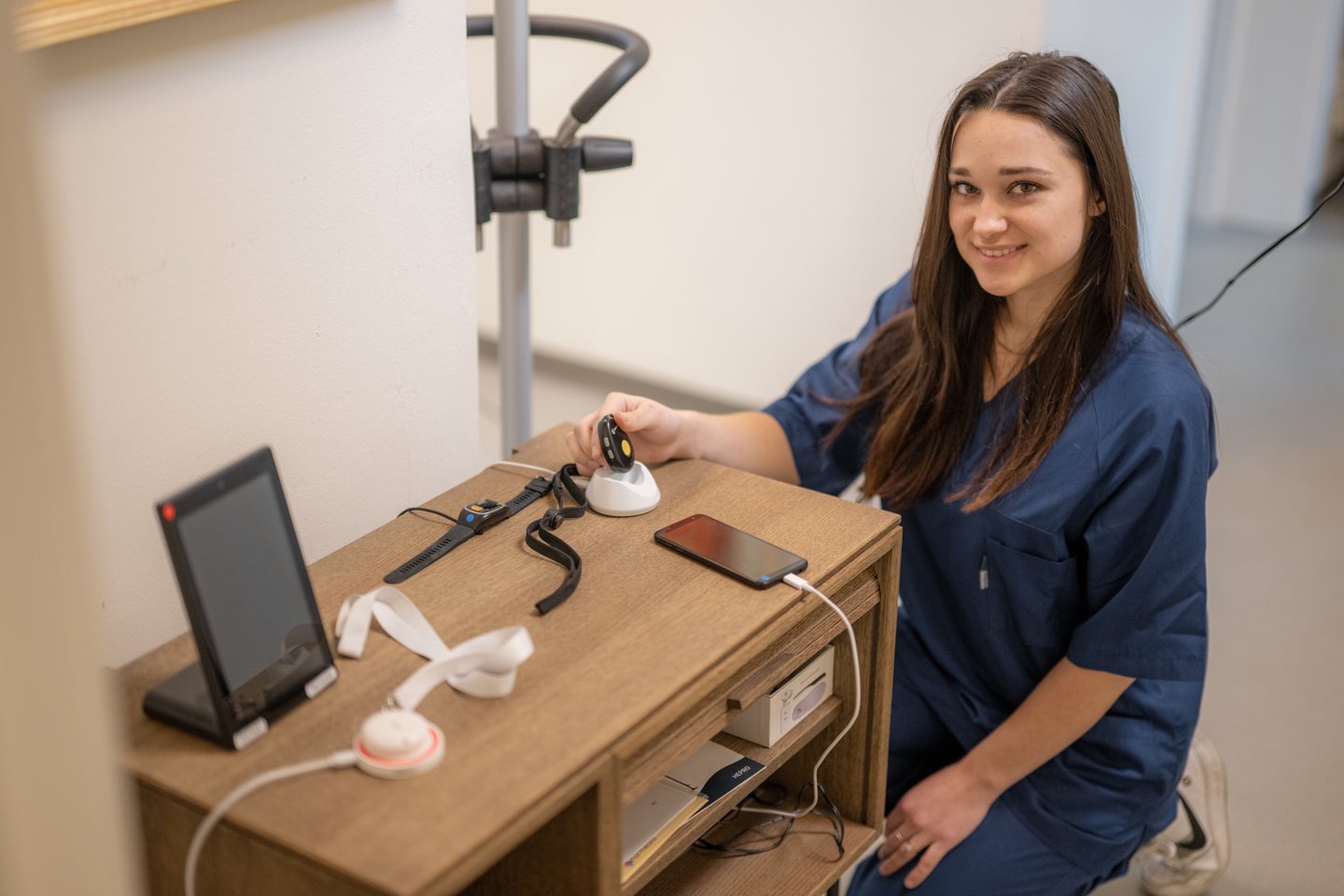 Helsepersonell smiler inn i kamera ved et bord med tekniske instrumenter.