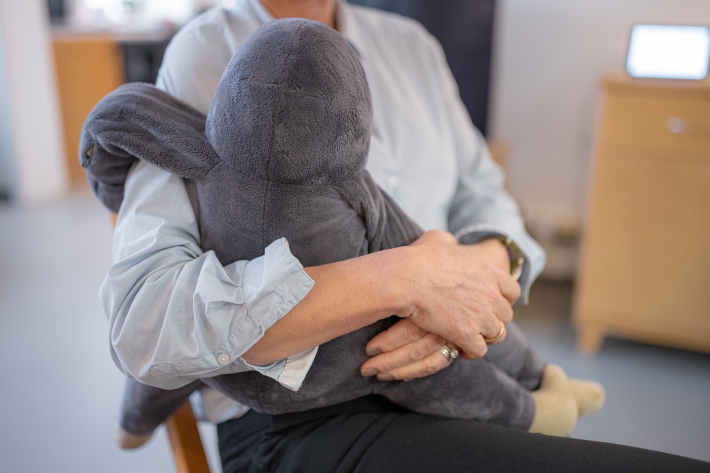 En person sitter og holder et mykt og stort kosedyr som brukes i velferdsteknologi