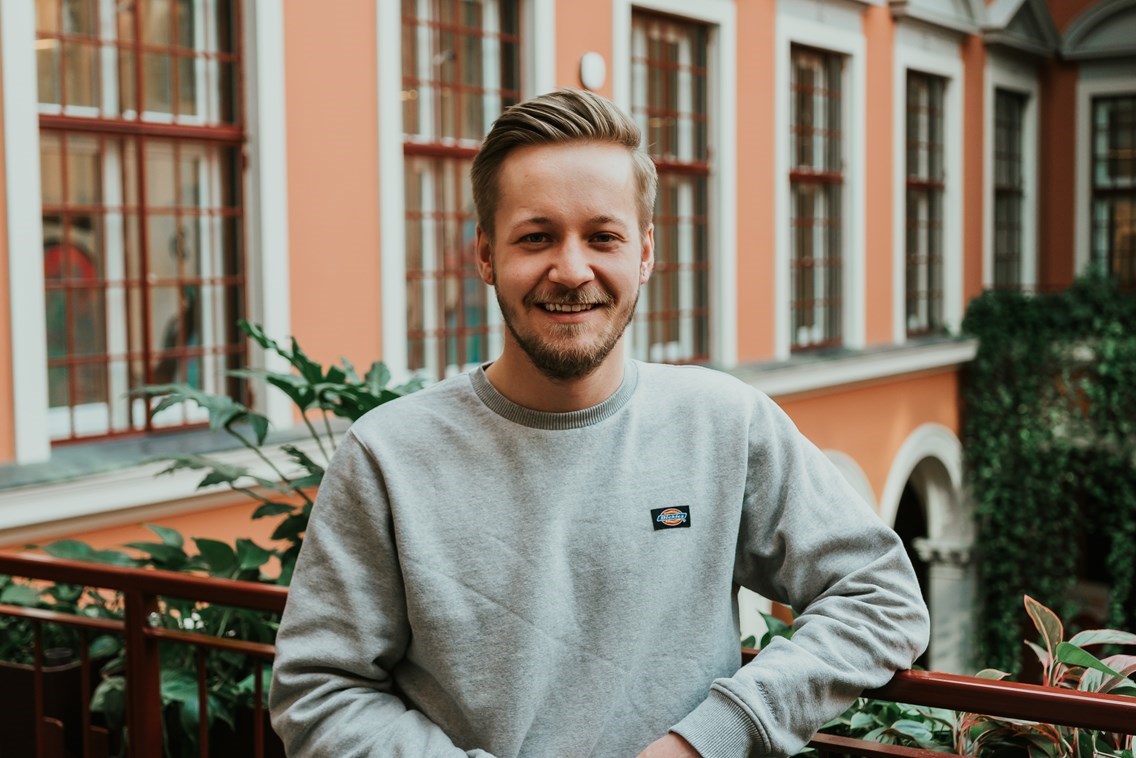 Portrettfoto av en mann som smiler i kamera på campus i Oslo.