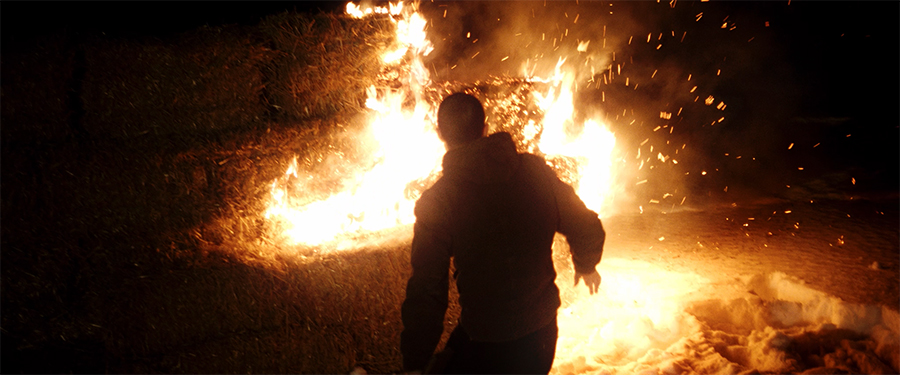 Silhuett av person som ser på store flammer.