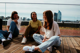Tre studenter som sitter på takterrassen i Urtegata med utsikt over Oslo
