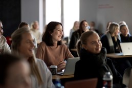 Foto av studenter i klasserom som koser seg med undervisningen som skjer foran dem.