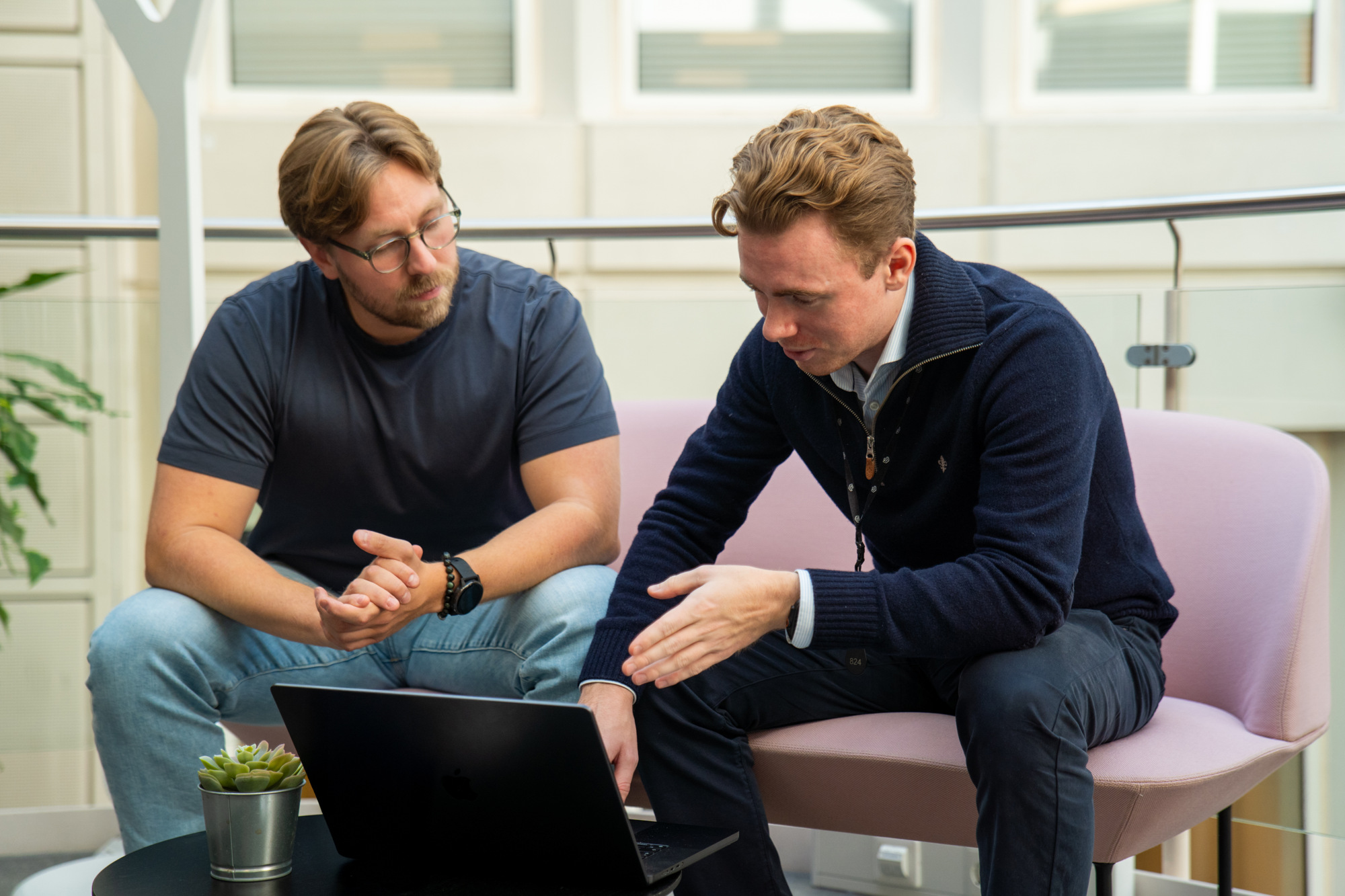 Linus og Dennis sitter i den rosa sofaen på Dibbel-kontoret, med blikket rettet mot PC-skjermen foran dem.