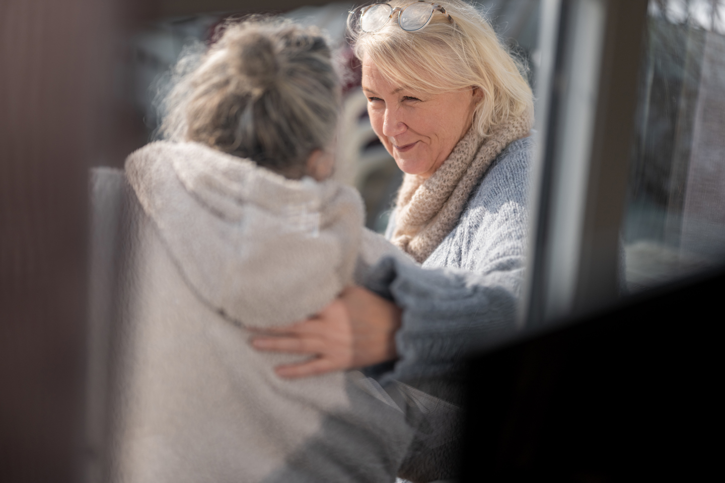 To personer sitter tett sammen utendørs og holder rundt hverandre og viser omsorg