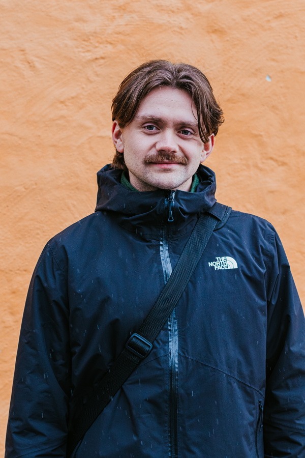 Bilde av Tomas Hogseth foran oransje vegg.