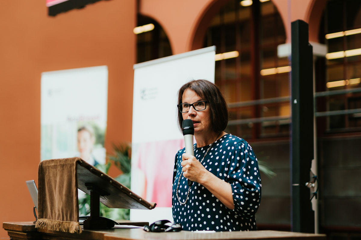 Kvinne står på talerstolen under en konferanse.