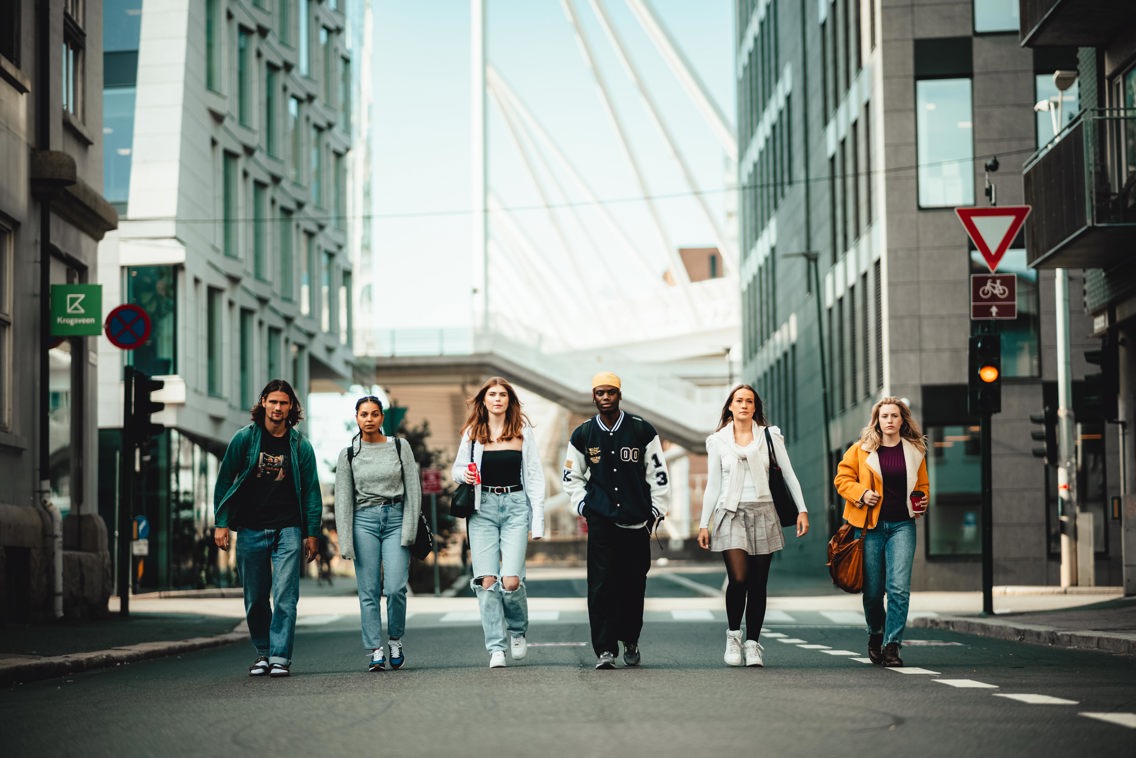 Foto av studenter som spaserer lans en bilvei i en by