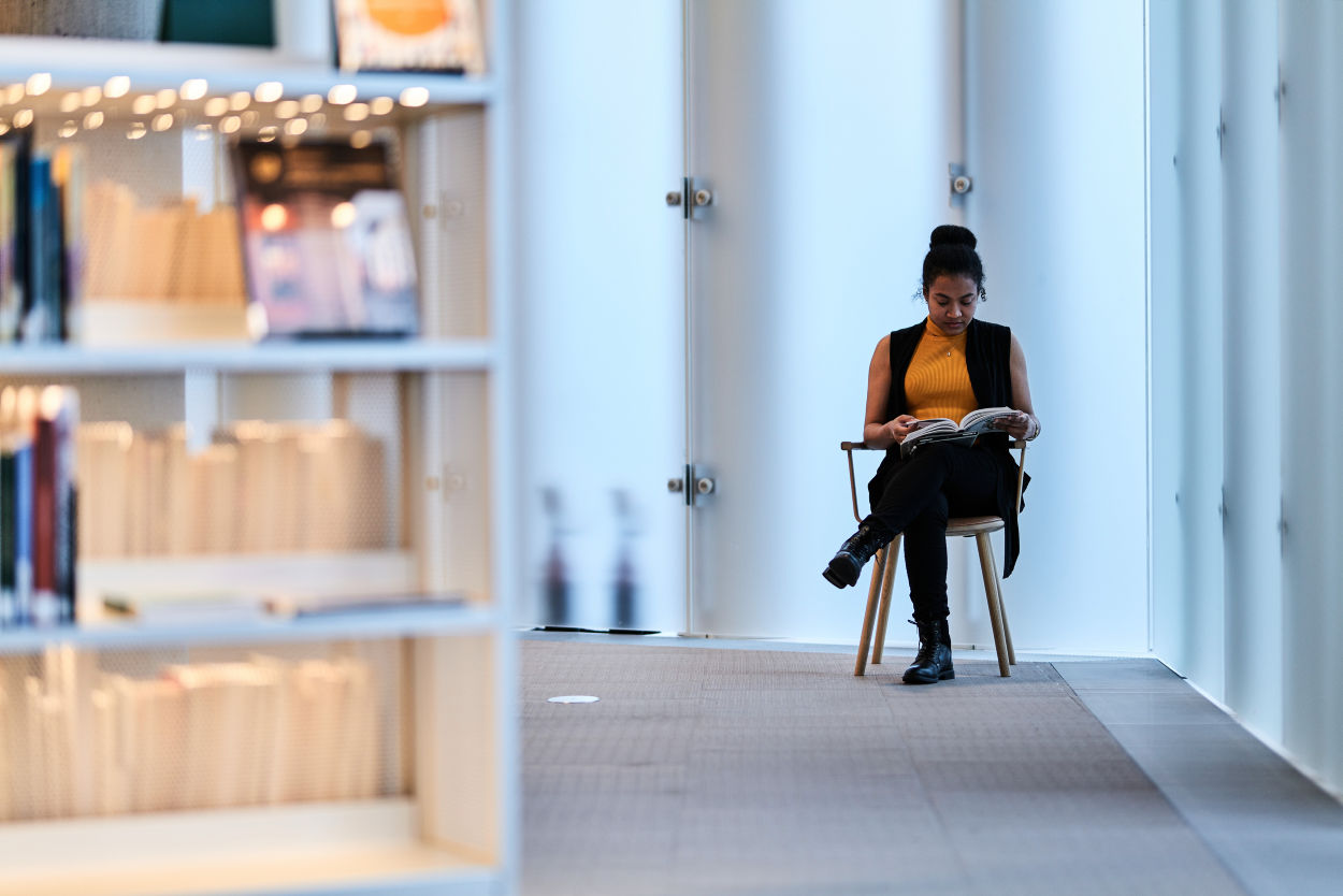 Kvinne leser en bok på et moderne bibliotek