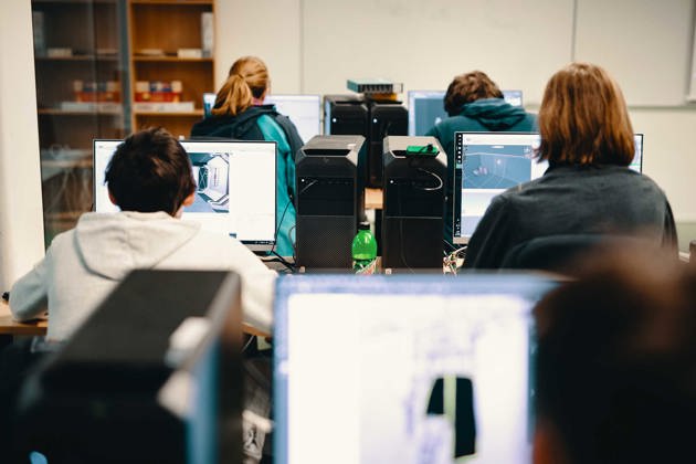 Studenter sitter i klasserommet og jobber på datamaskiner. 