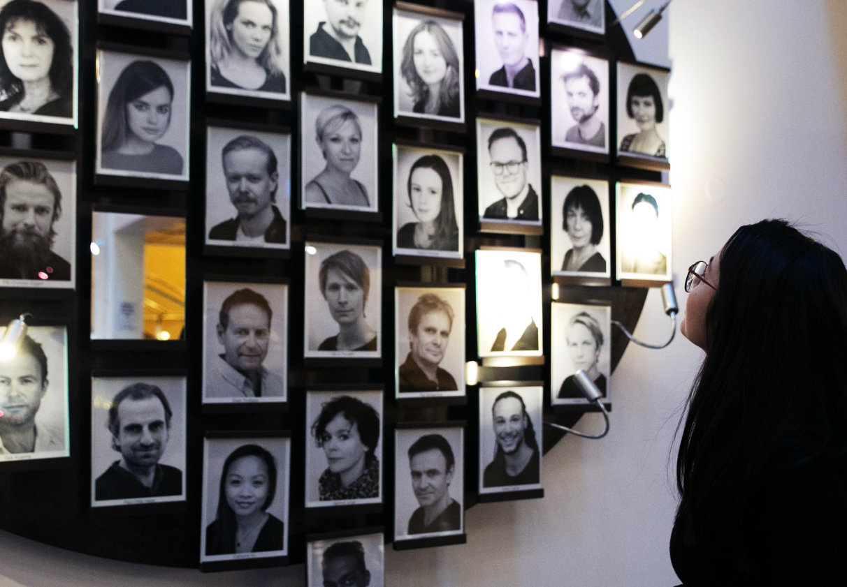 Andrea studerer veggen med portretter av skuespillerne ved Det Norske Teatret.