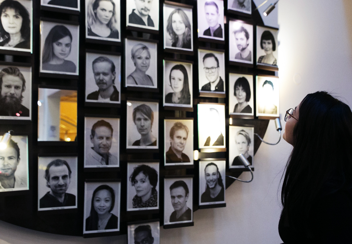Andrea studerer veggen med portretter av skuespillerne ved Det Norske Teatret. 