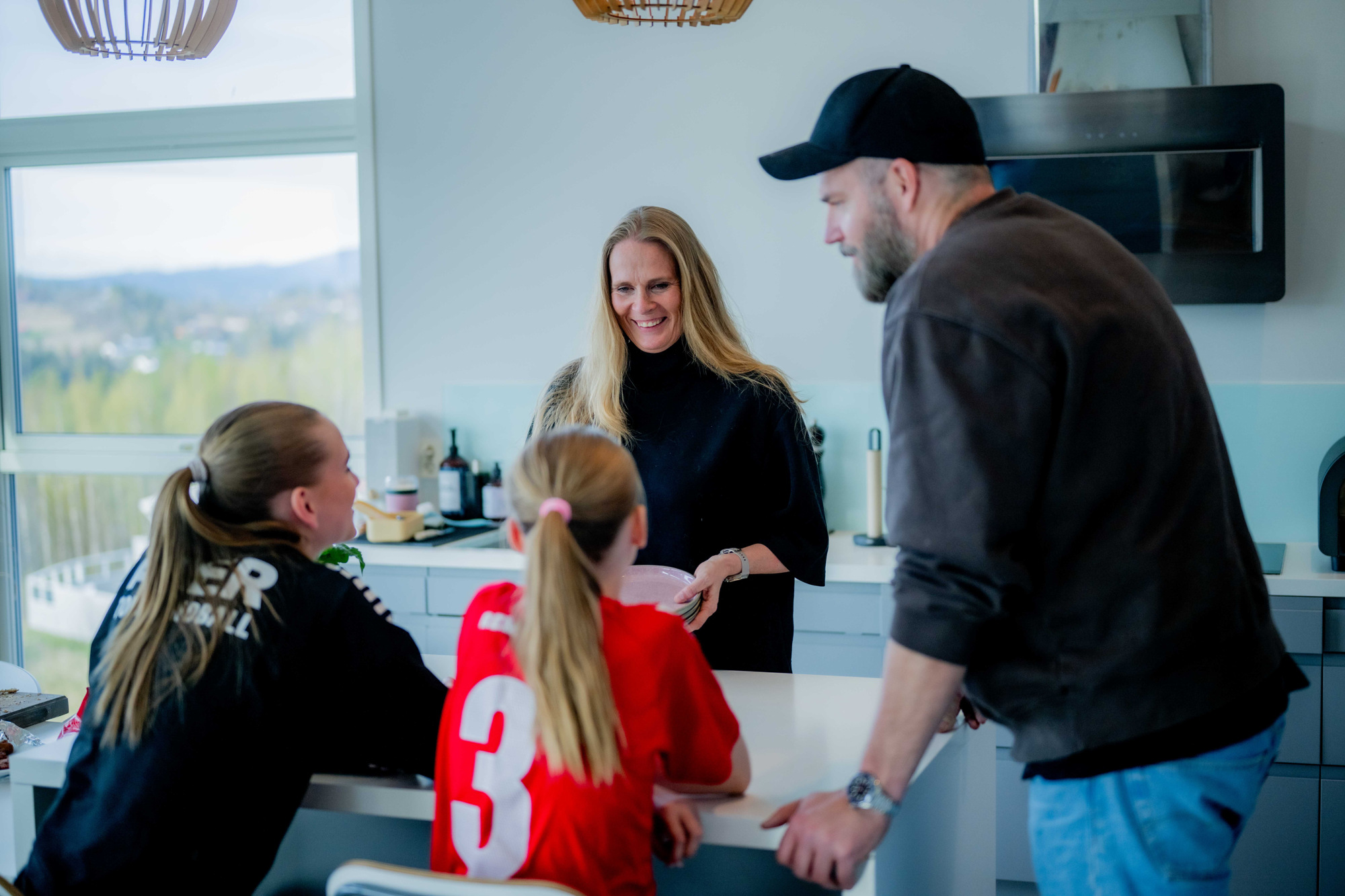 Guro, mannen hennes og deres to barn er samlet rundt kjøkkenøya hjemme.