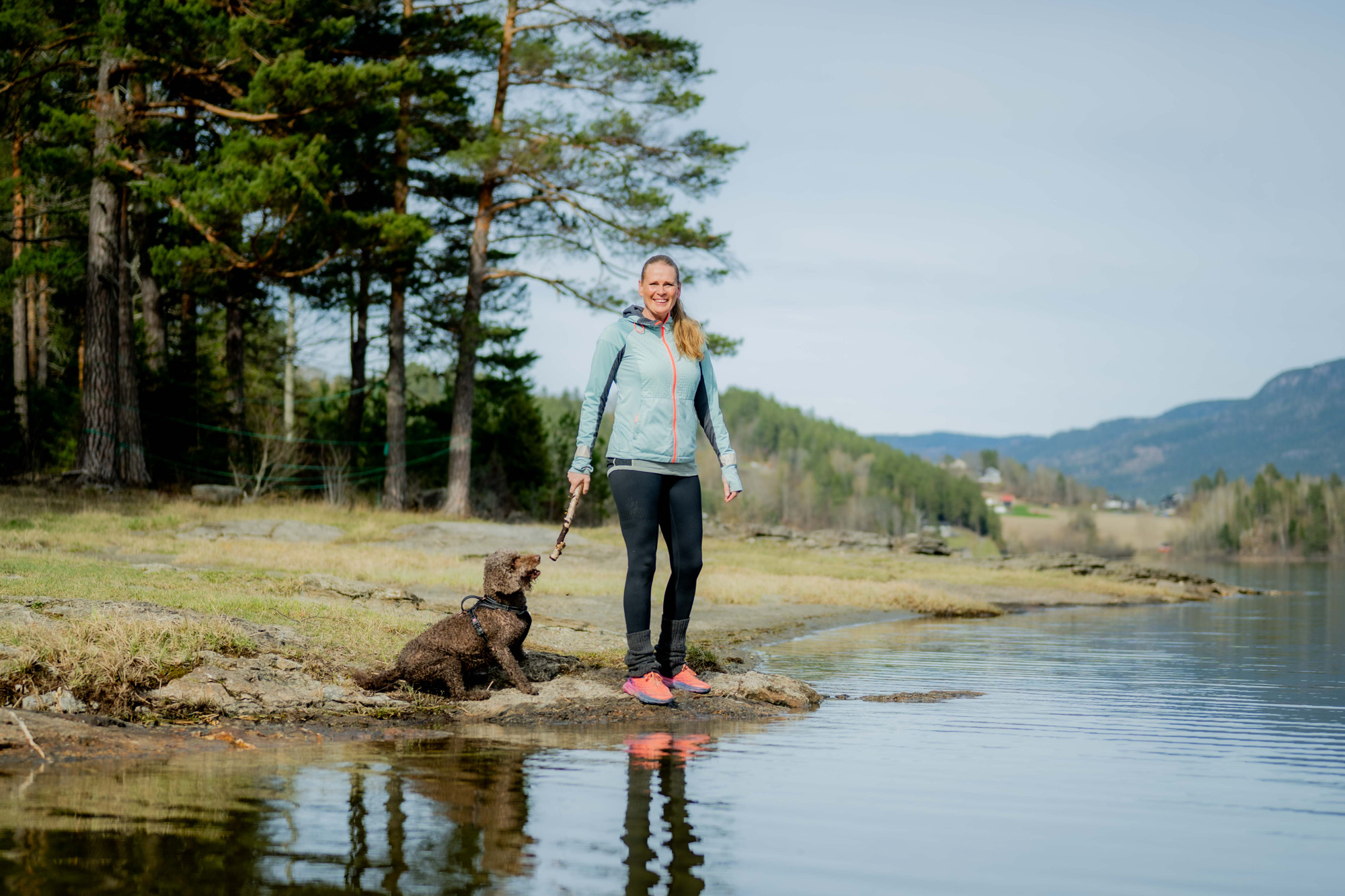 Guro som er ute på tur med hunden sin i skogen rundt et vann