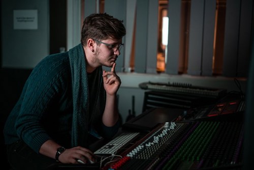 En student som sitter foran en miksepult og jobber