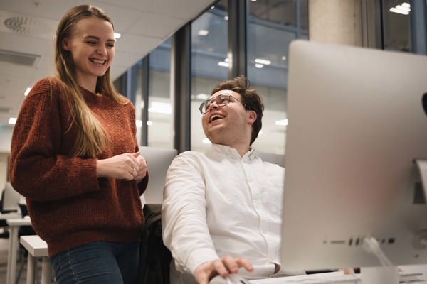 To personer ler foran en datamaskin. 