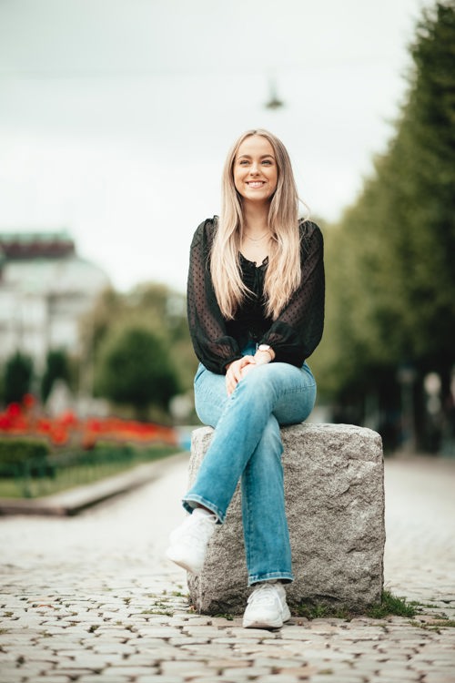 Anniken sitter på en sten ved brostein.