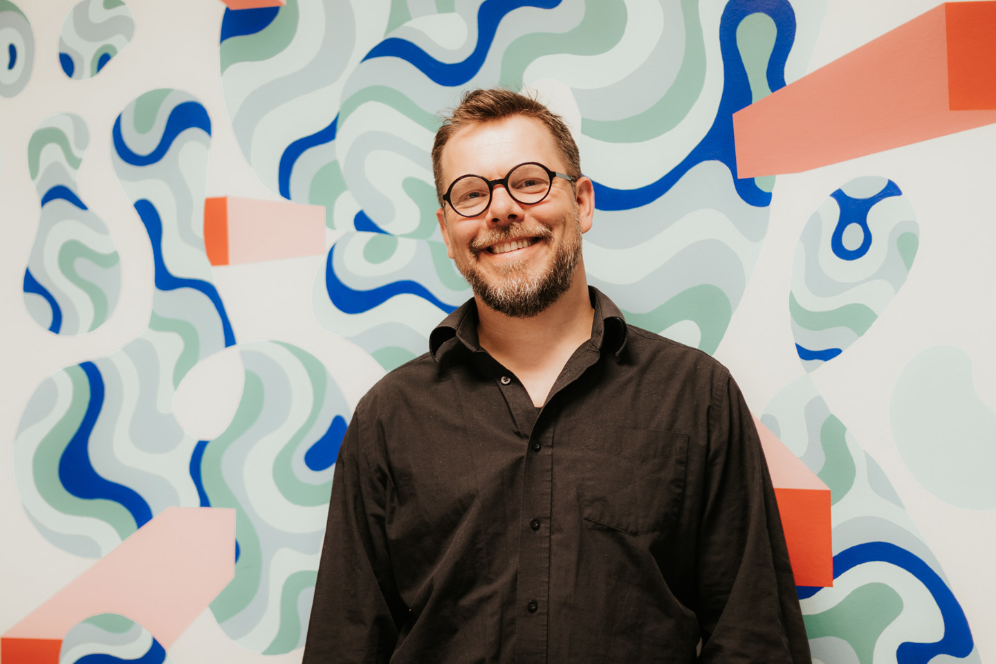 Bilde av Tor Edvin Strøm foran kunstvegg.