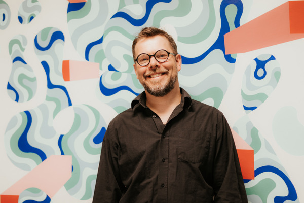Bilde av Tor Edvin Strøm foran kunstvegg.