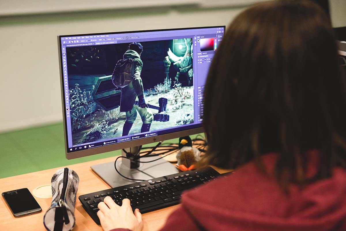 En student sitter ved en PC og jobber med et dataspill. 