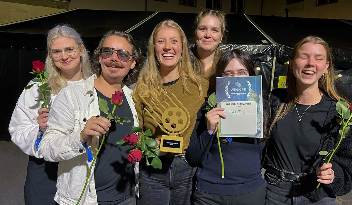Foto av vinnerne av publikumsprisen under Amandus Blikkfang 2021, som holder frem en pokal og blomster.