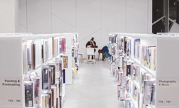 En kvinne sitter mellom radene på et bibliotek og jobber