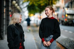 To unge kvinner i samtale på et fortau i Oslo sentrum.