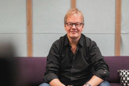 Audun Molde som smiler inn i kamera mens han sitter på en lilla sofa
