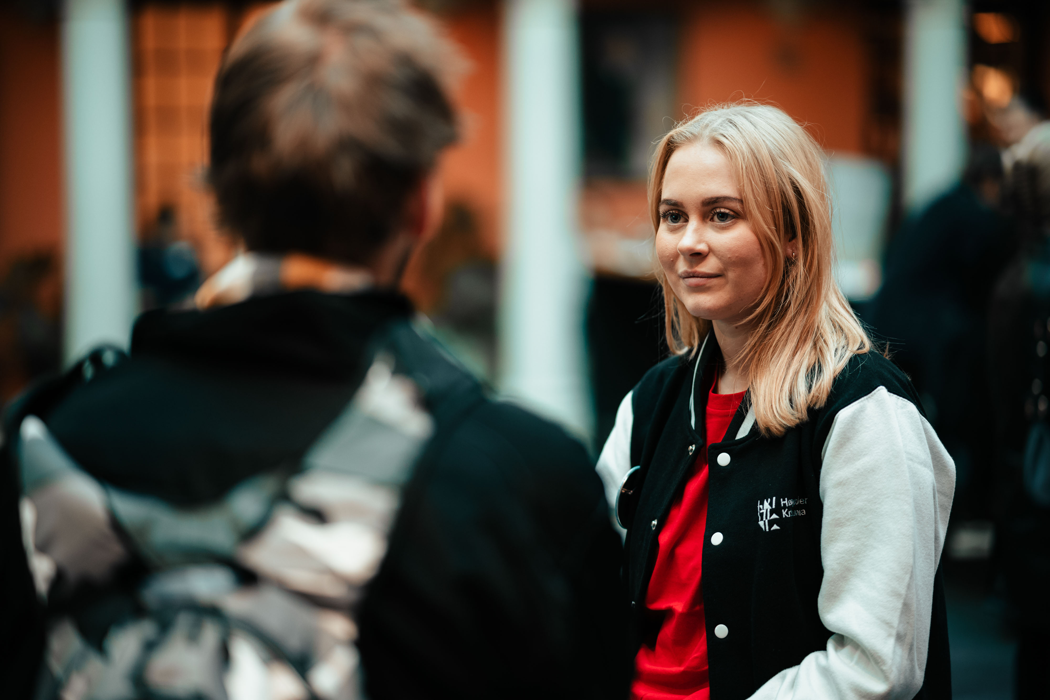 Kvinne i Kristiania-jakke smiler til besøkende.