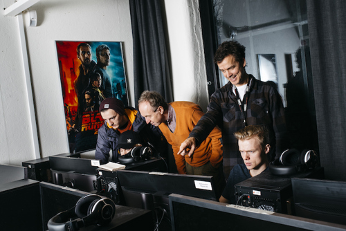 Gruppefoto av tre studenter og en veileder som arbeider på PC-er.