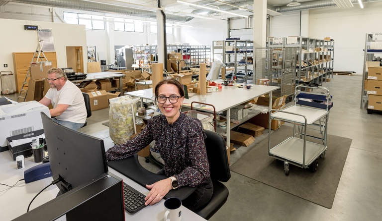 To personer sitter inne på et logistikklager foran PC