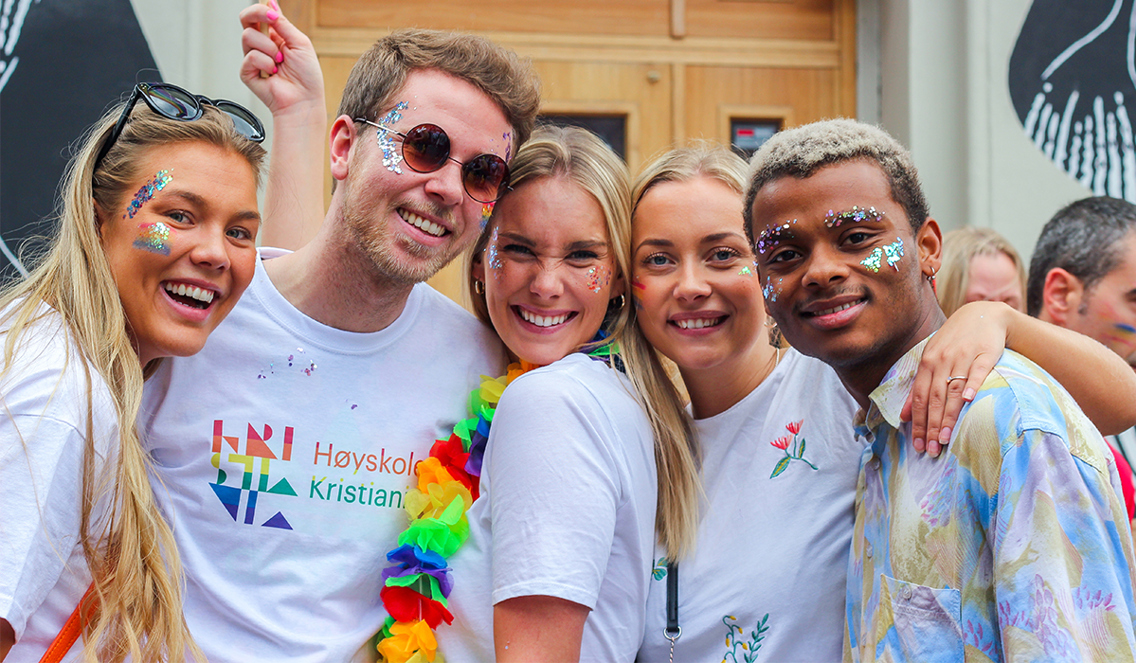 Fem studenter smiler til kamera. De har glitter i ansiktet og hk-tskjorter!