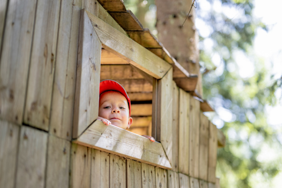 Et barn titter ut av vinduet til en trehytte