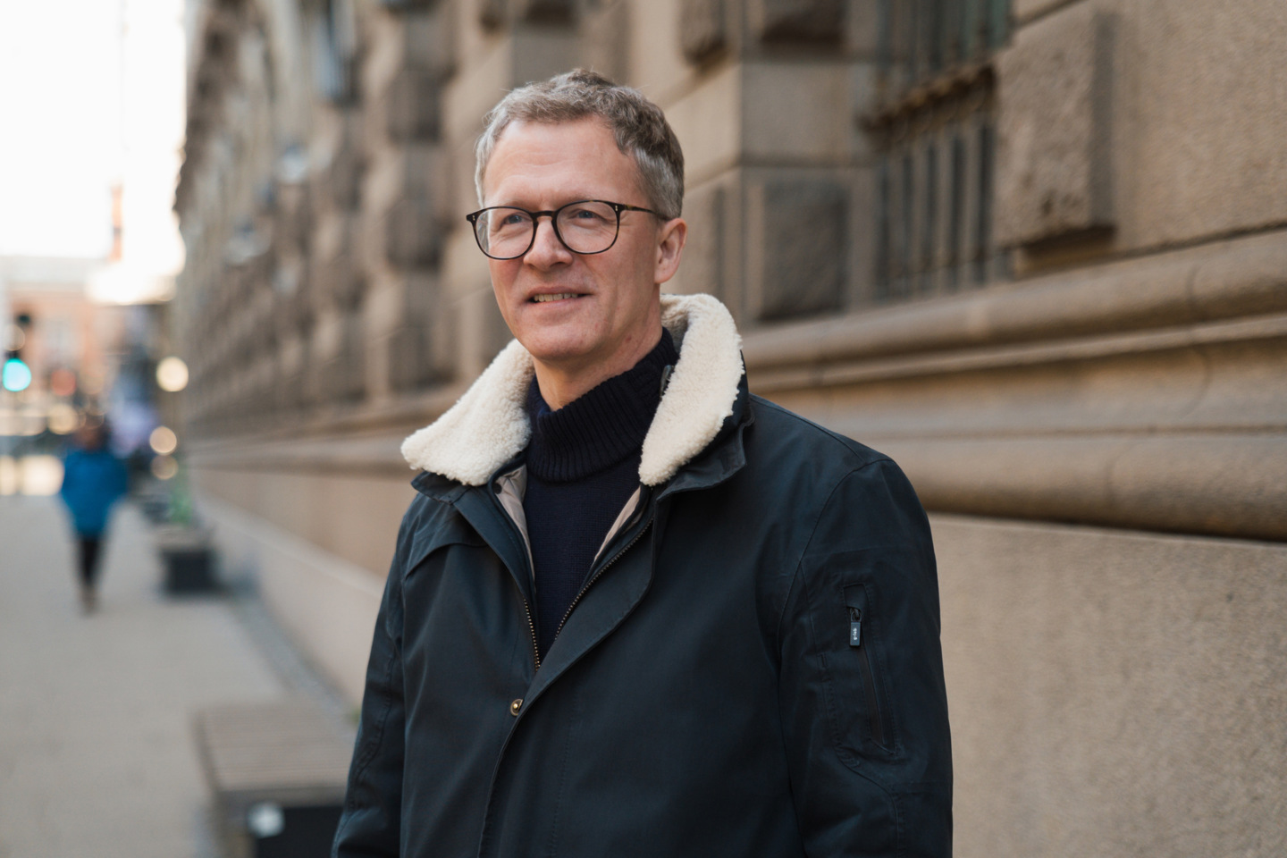 Portrett av Inge som står ute i gaten med bygninger i bakgrunnen. 