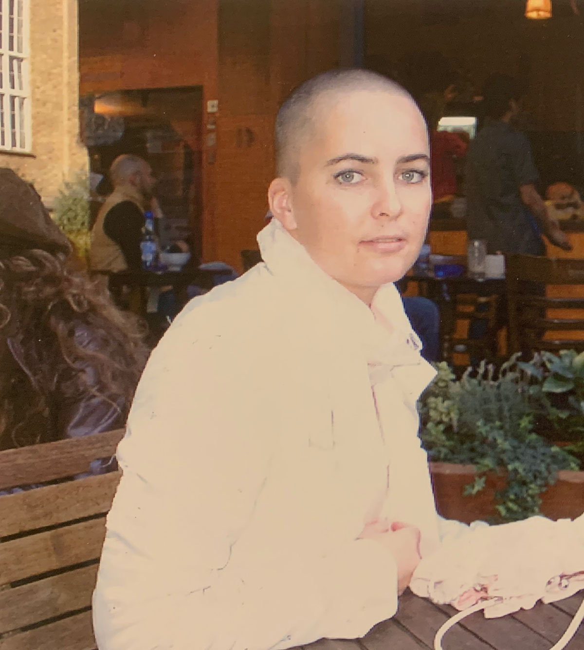 Foto av kvinne med kortbarbert hår som sitter på en benk.