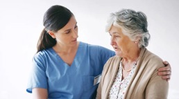 A nurse holds her arm around her older patient