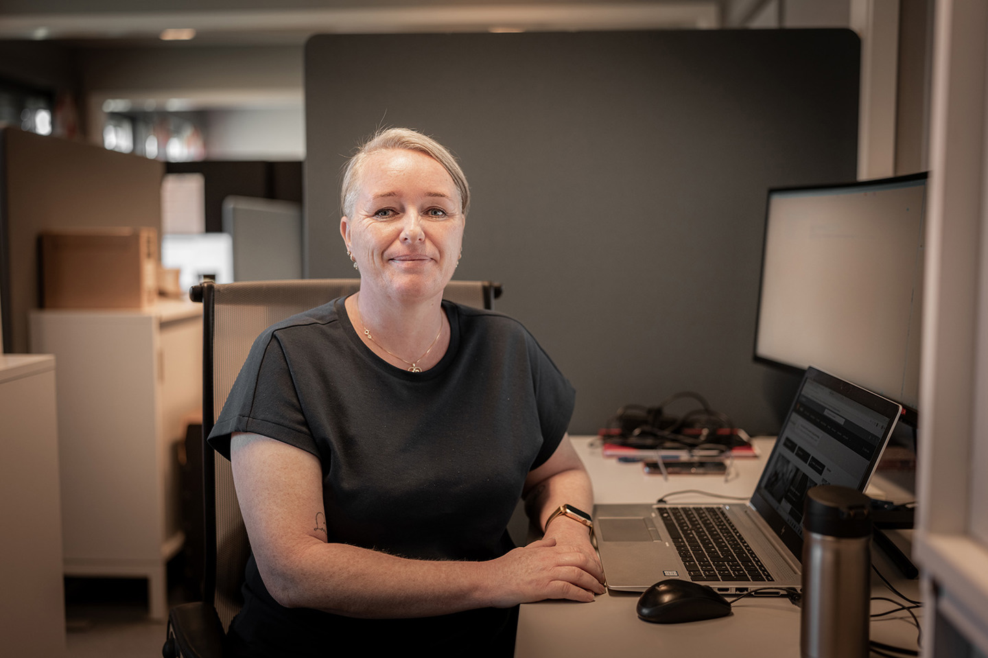 Solfrid Hansen Obbink sitter ved en kontorpult og smiler til kamera