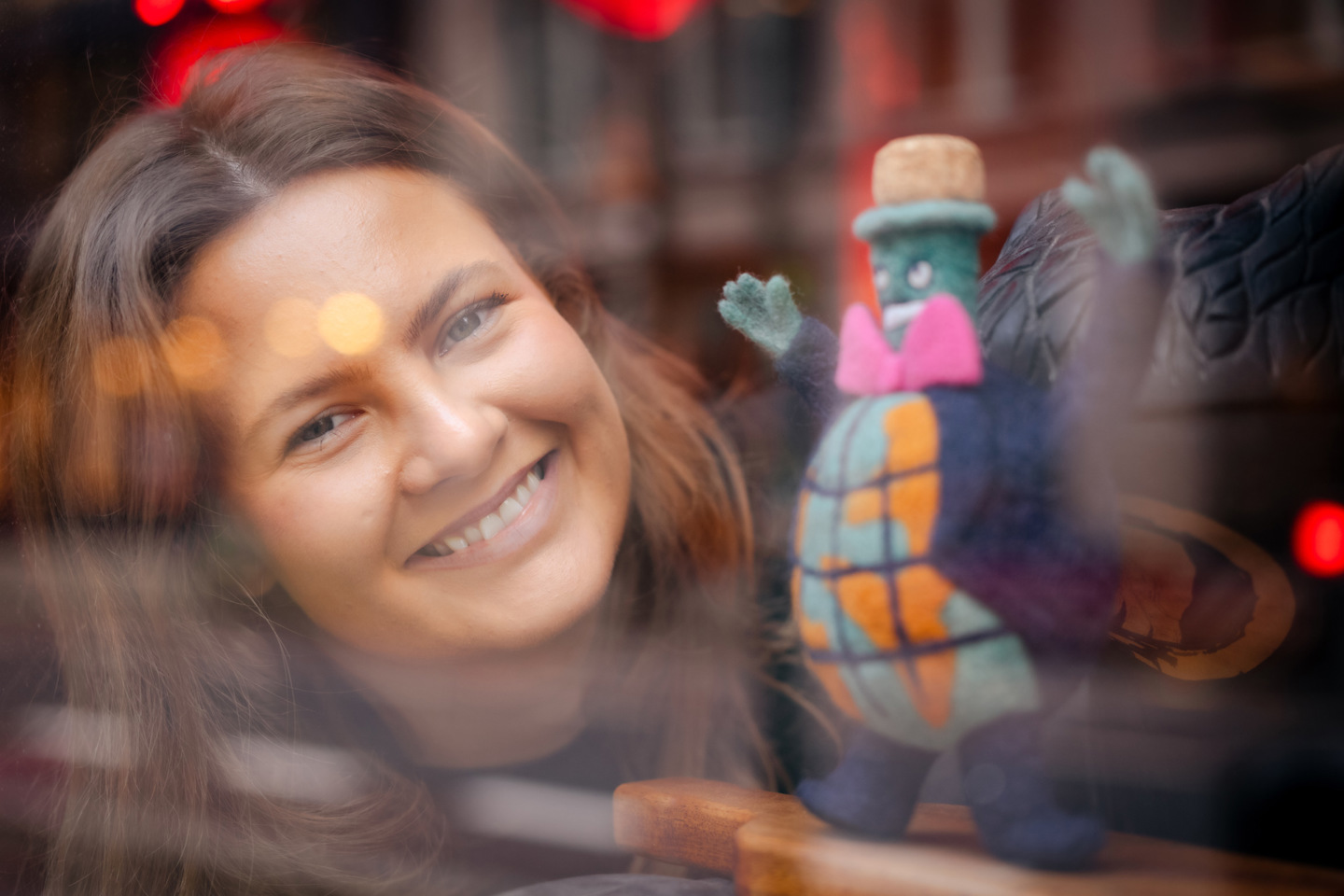 Amanda smiler gjennom vinduet ved siden av en flaske på småflaskemuseet.