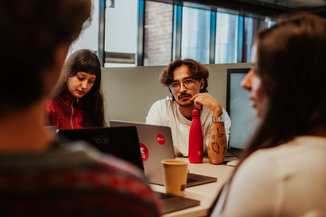 Fire studenter som diskuterer i gruppe rundt et bord
