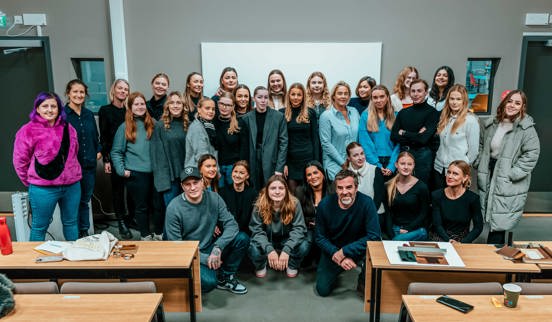 Interiørstudentene smilende i klasserommet sammen med deleierne OnklP og Mats. 