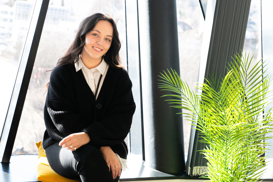 Bilde av Helene Moe som sitter i vinduskarmen i kontorlokalet til VIsma.