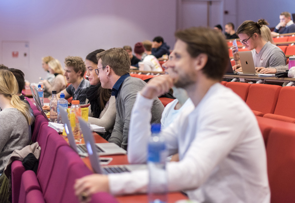 Bilde av studenter med laptop i en forelesning i et auditorium.