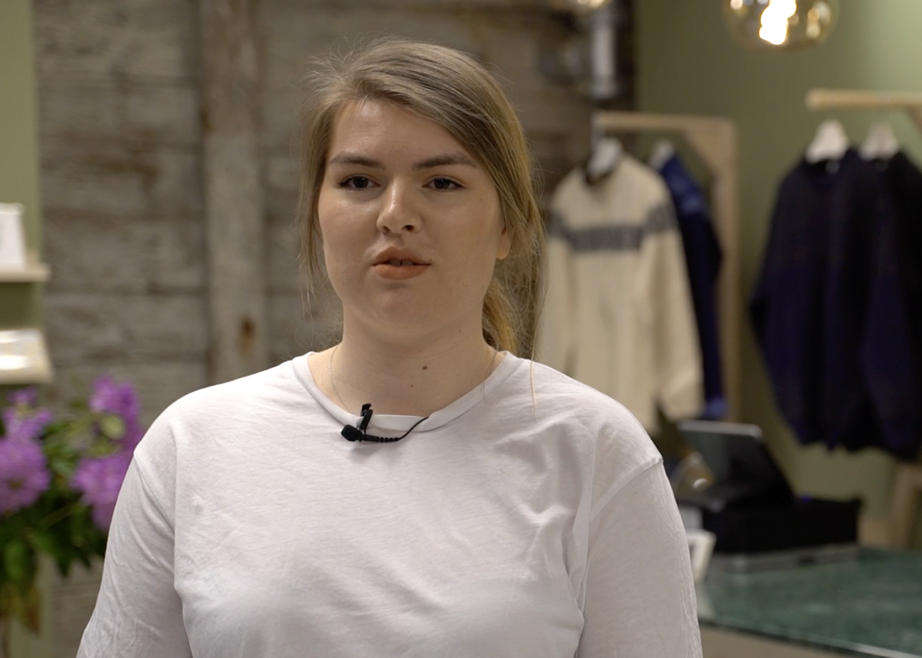 Foto av kvinnelig student i butikken hun har designet.
