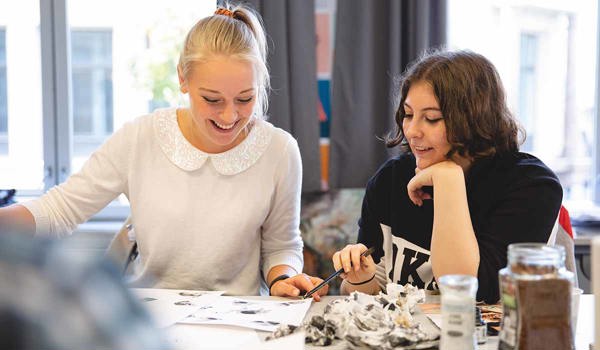 Illustrasjonsstudenter på Fagskolen Kristiania sitter og maler.