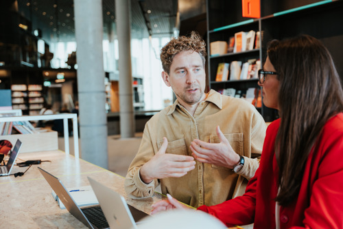 Bildelenke av to voksne studenter som snakker sammen.