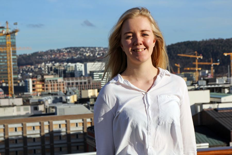 Foto av Andrea Grøndal Berg på takterasse med by i bakgrunnen.