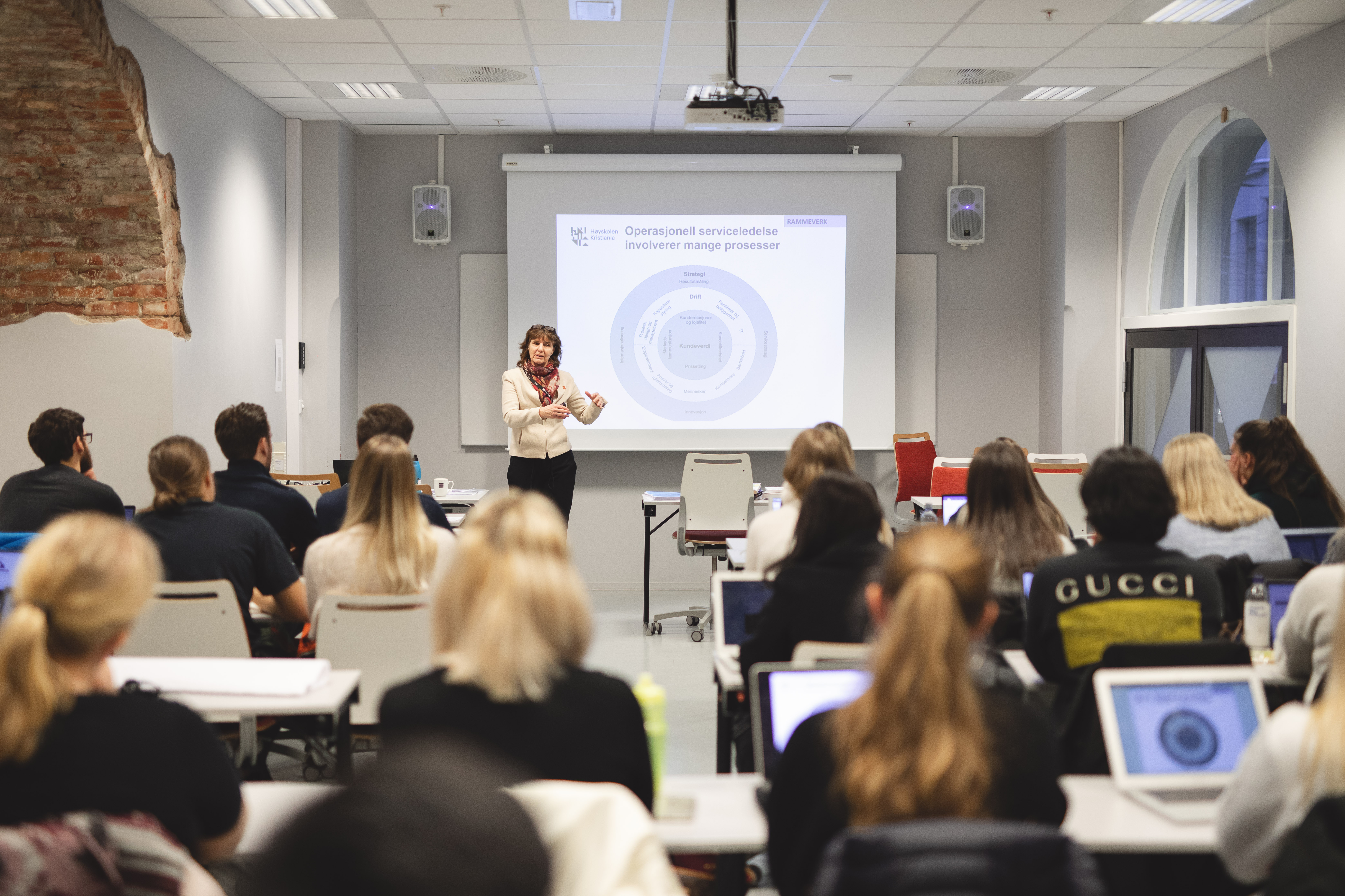 Kvinnelig foreleser med power point presentasjon i klasserom med studenter