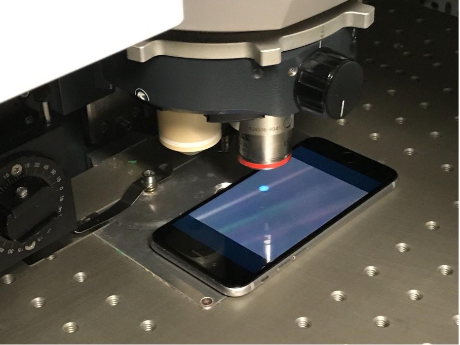 Utstillingen Pale Blue Dot, med en telefon med et teleskoplignende verktøy over med en svak lyseblå prikk på iPhone-skjermen